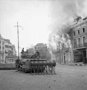 The British Army in North-west Europe 1944-45 A Sherman Crab flail tank in front of burning buildings in Arnhem, 14 April 1945.