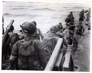 American soldiers with full equipment leap into surf from LCVP wading toward Utah Beach at Les Dunes de Madeleine — Signal Corps SC-320884 — 6 June 1944