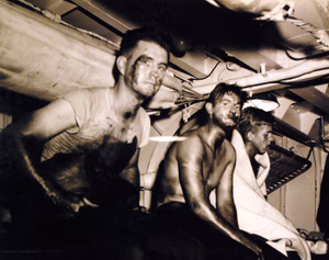 80-G-54606: Invasion of Sicily, September 1943. USS Rowan (DD 405). Three survivors smeared with oil and blood awaiting medical attention following the sinking of their ship in Italian waters as a result of an underwater explosion. Photograph released September 25, 1943. U.S. Navy Photograph, now in the collections of the National Archives. (2016/11/25).