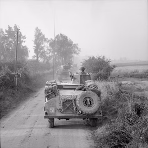 A Morris light reconnaissance car and, in the background, Sherman Crab flail tanks move up to the battle area for Operation 'Goodwood', 18 July 1944.