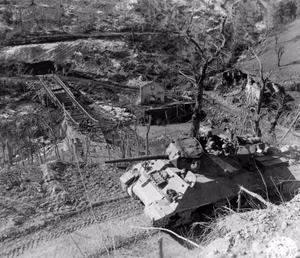 In background is a half-finished bailey bridge and a Sherman tank that is out of action. 3 March, 1945. 701st Tank Destroyer Battalion, 10th Mountain Division. Photographer: Baker, 196th Signal Photo Co.