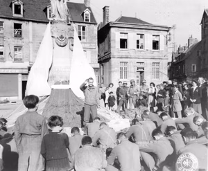The monument, draped with parachutes, is a World War 1 tribute from the citizens of Carentan to its soldier dead. 19 June, 1944. 101st Airborne Division. Photographer: Collier. Photo Source: U.S. National Archives. Digitized by Signal Corps Archive.