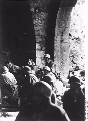 For documentary purposes the German Federal Archive often retained the original image captions , which may be erroneous, biased, obsolete or politically extreme . Unter den Trümmern von Cassino. Deutsche Fallschirmjäger kämpfen tapfer weiter