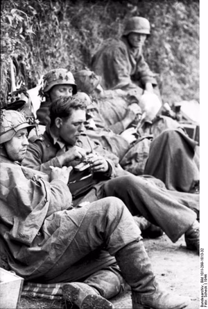 Frankreich-Nord.- Erschöpfte Infanteristen bei Rast an einer Böschung ruhend / liegend, Soldat beim Essen aus einer Dose; PK 698 — Nordfrankreich