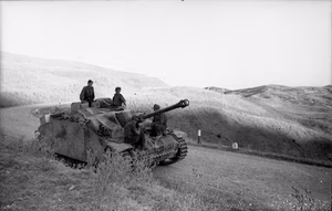 Italien.- Soldaten auf Sturmgeschütz III mit Seitenschürzen bei Fahrt auf befestigter Straße in hügeliger Landschaft; PK 699 — Italien, World War II, unknown town
