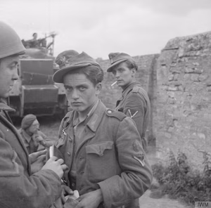 The British Army in the Normandy Campaign, 1944 German prisoners being searched by British troops near St. Gabriel, 7 June 1944. Both men claimed to be Polish, and had Polish army badges stuck in the fronts of their field caps.