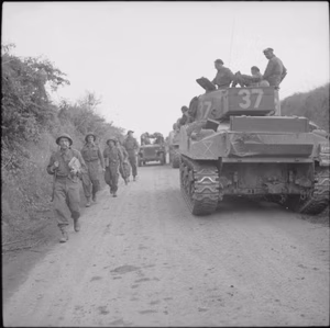 The British Army in the Normandy Campaign 1944 Infantry pass Sherman tanks of 33rd Armoured Brigade near Lebisey Wood, during Operation 'Charnwood', 8 July 1944.