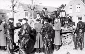 Belgien/Frankreich.- Gruppe von Panzermännernder Waffen-SS während einer Rast auf und um leichten Zugkraftwagen stehend, in einer Ortschaft; Soldat mit Ziehharmonika; PK 698 — Im Westen